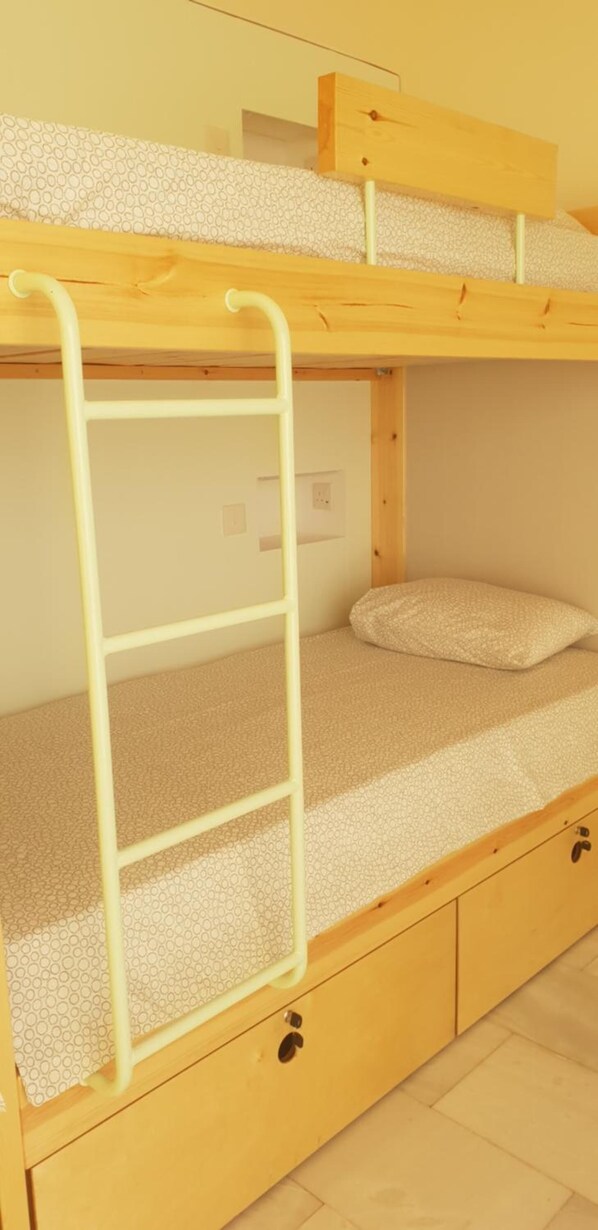 A bunk bed with a ladder, a pillow, and a drawer. - NEX Hostel (Egkomi)