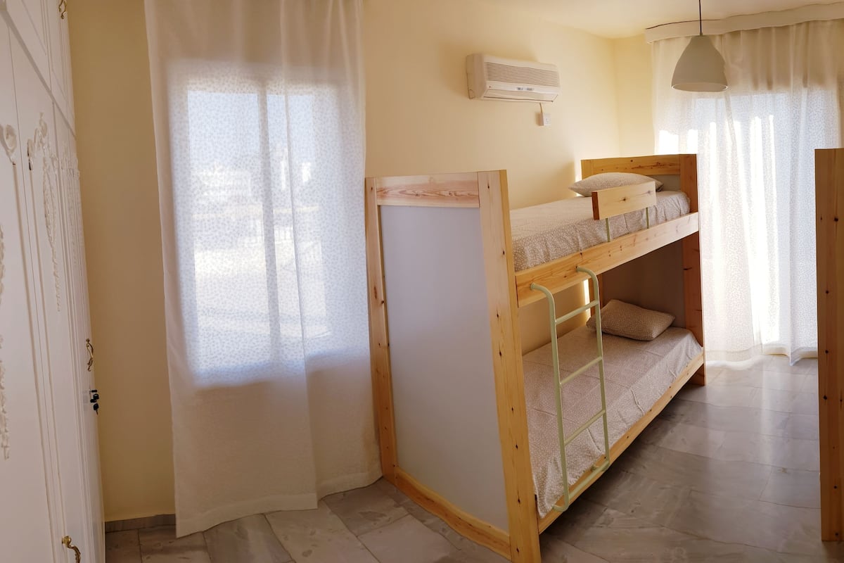 A room with a bunk bed, a radiator, and a window with curtains.