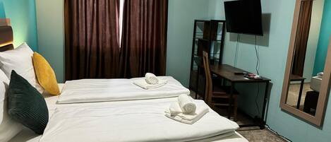 Habitación de hotel con dos camas, un escritorio, una silla, un televisor y un espejo.