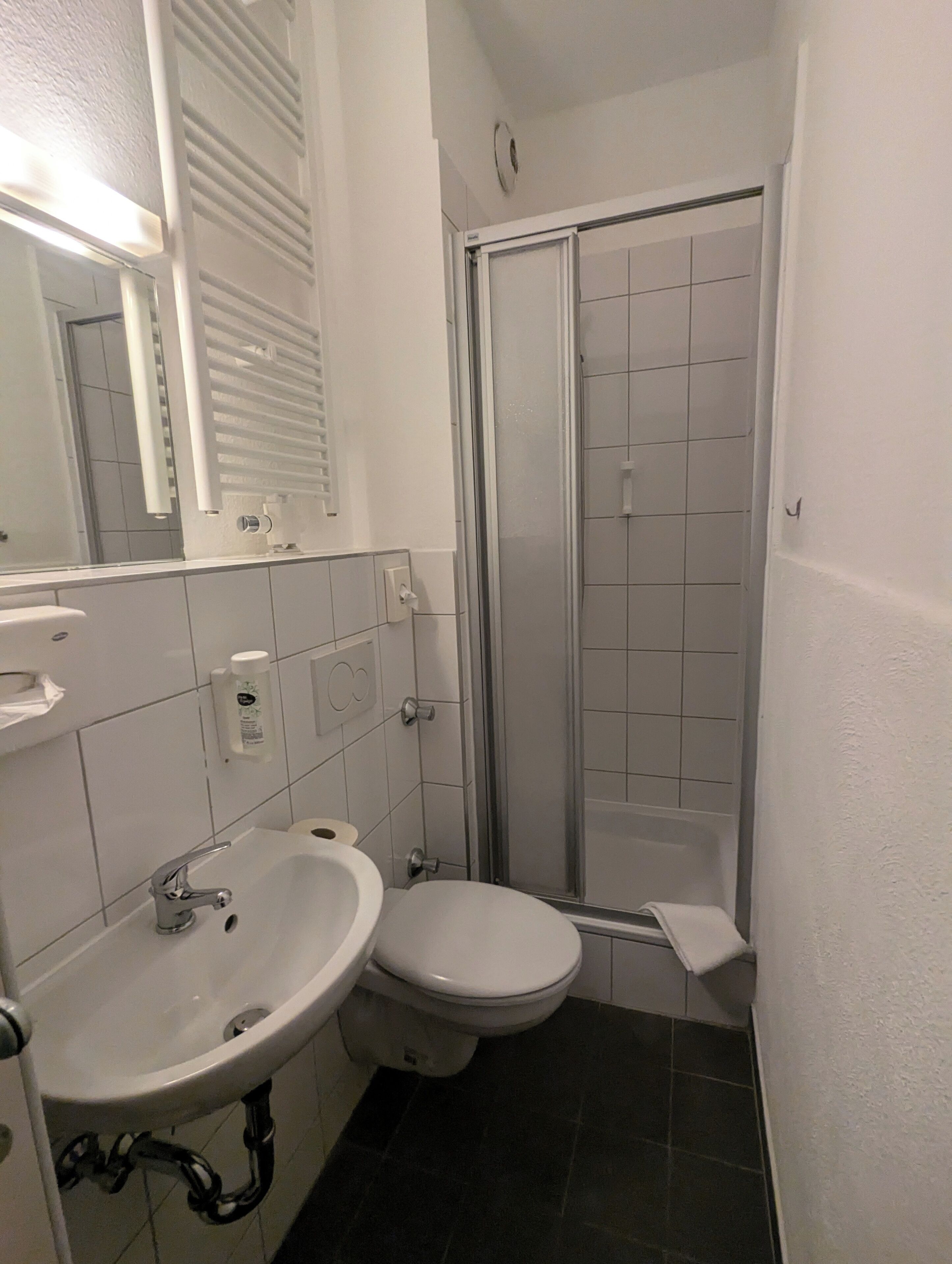 Et badeværelse med hvid vask, toilet og brusekabine i glas.