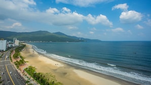 Una carretera costera con playa y montañas al fondo.