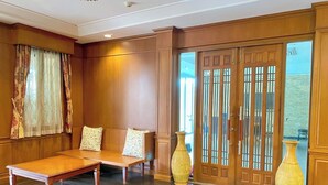 Una habitación con un banco de madera, un jarrón grande y un puertas corredera con diseño tradicional.