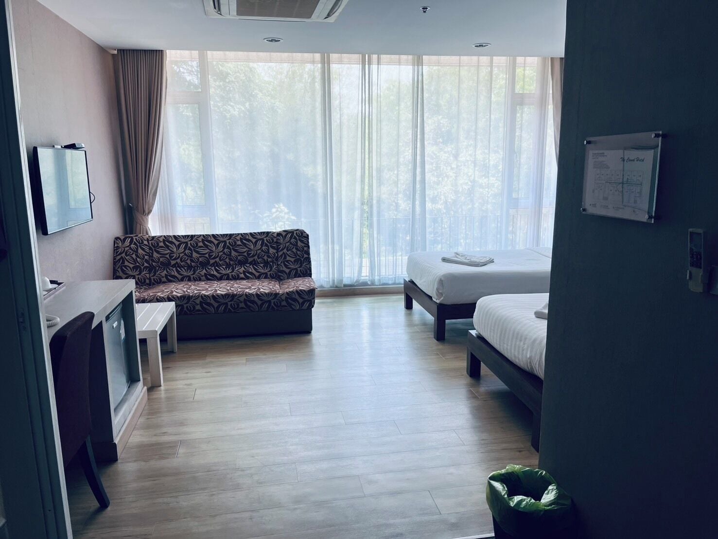 Una camera d'albergo con un divano, un letto, una scrivania e un cestino.