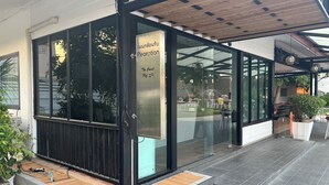 Un edificio moderno con área de recepción, puertas de cristal y un espacio al aire libre cubierto.