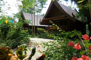 Guests can enjoy a serene natural setting surrounded by lush greenery and a traditional wooden building with a porch.