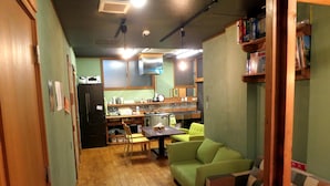 A compact kitchen with a dining area, a sofa, and a small table. - No Borders Hostel (Tokyo)