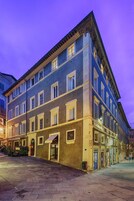 Un edificio a più piani con uno stile architettonico classico, caratterizzato da un ingresso a livello strada con tettoia e una vetrina ben visibile.