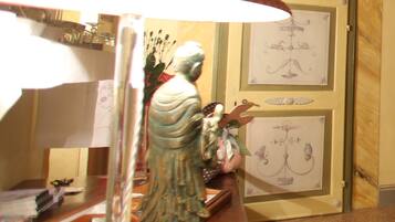Une pièce avec un plafond en bois, une lampe rouge, une statue et des œuvres d’art encadrées accrochées au mur.