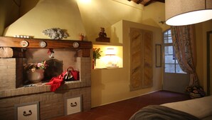 A cozy room with a fireplace, a bed, and a window with curtains. - B&B Le Aquile (Siena)