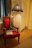 Una poltrona rossa imbottita con un libro intitolato "Monterosso" e una lampada con un paralume a righe.