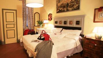Habitación de hotel con una cama grande, una mesita de noche, una lámpara, un cuadro en la pared y una puerta.