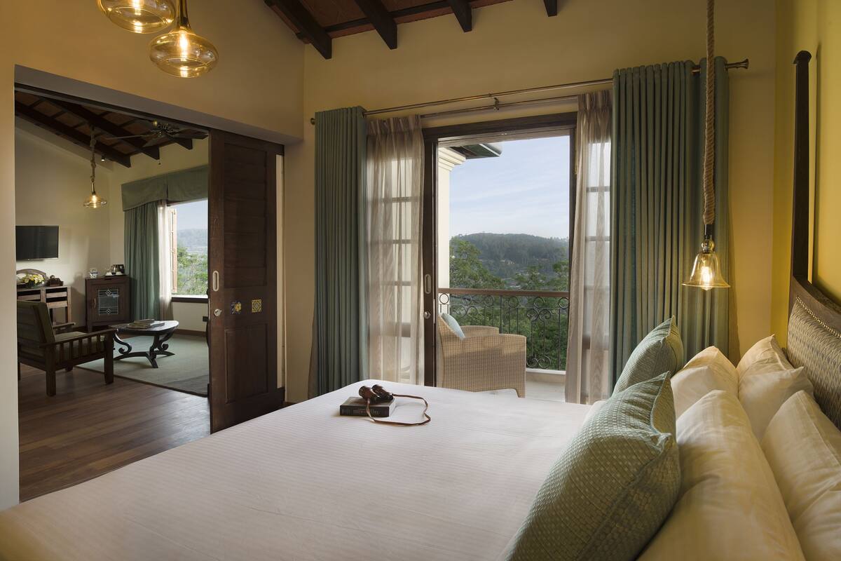 Une chambre dotée d’un grand lit, d’un balcon avec vue et d’un coin repas comprenant une table et des chaises.