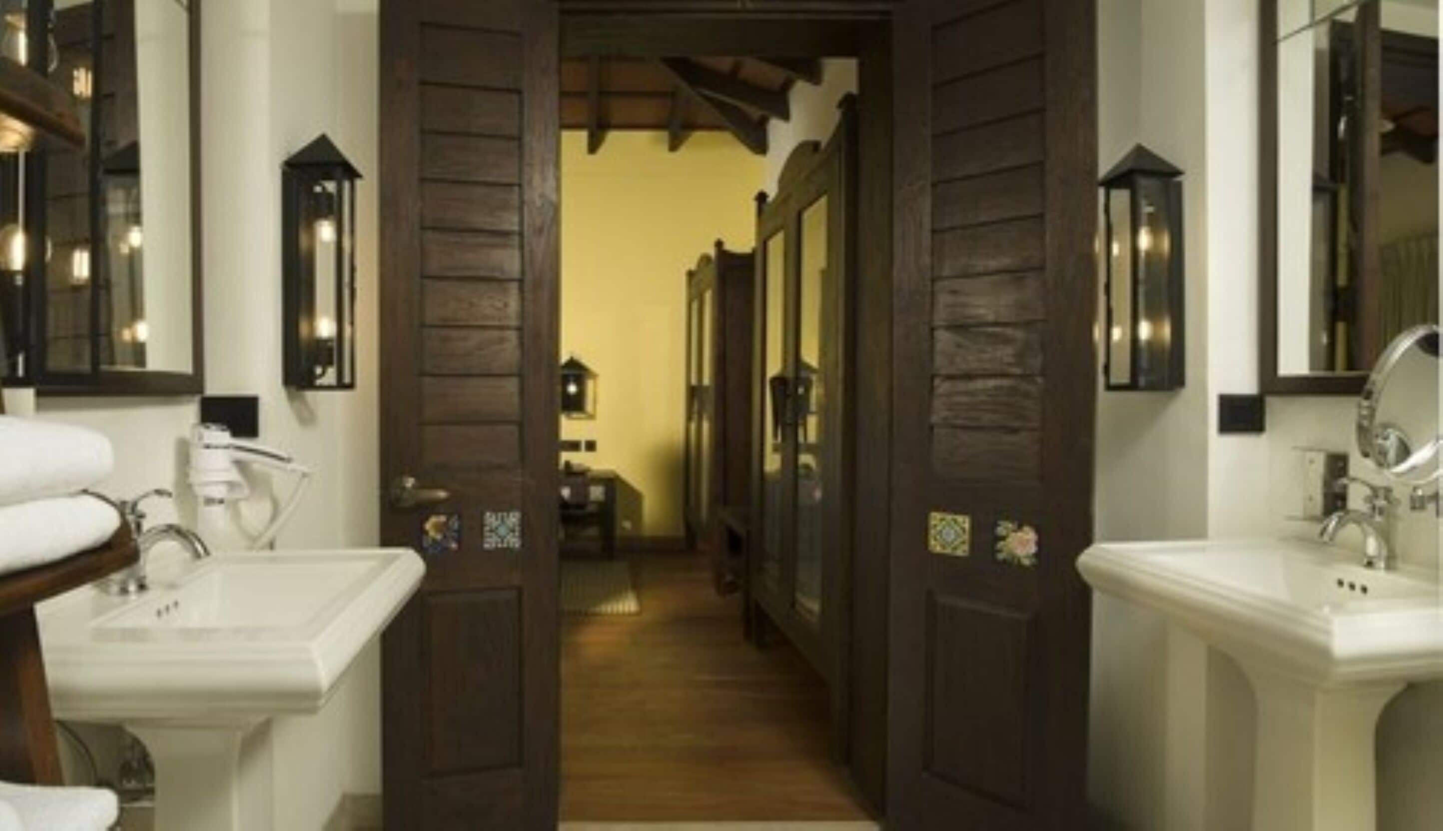A bathroom with wooden doors, white sinks, and mirrors.