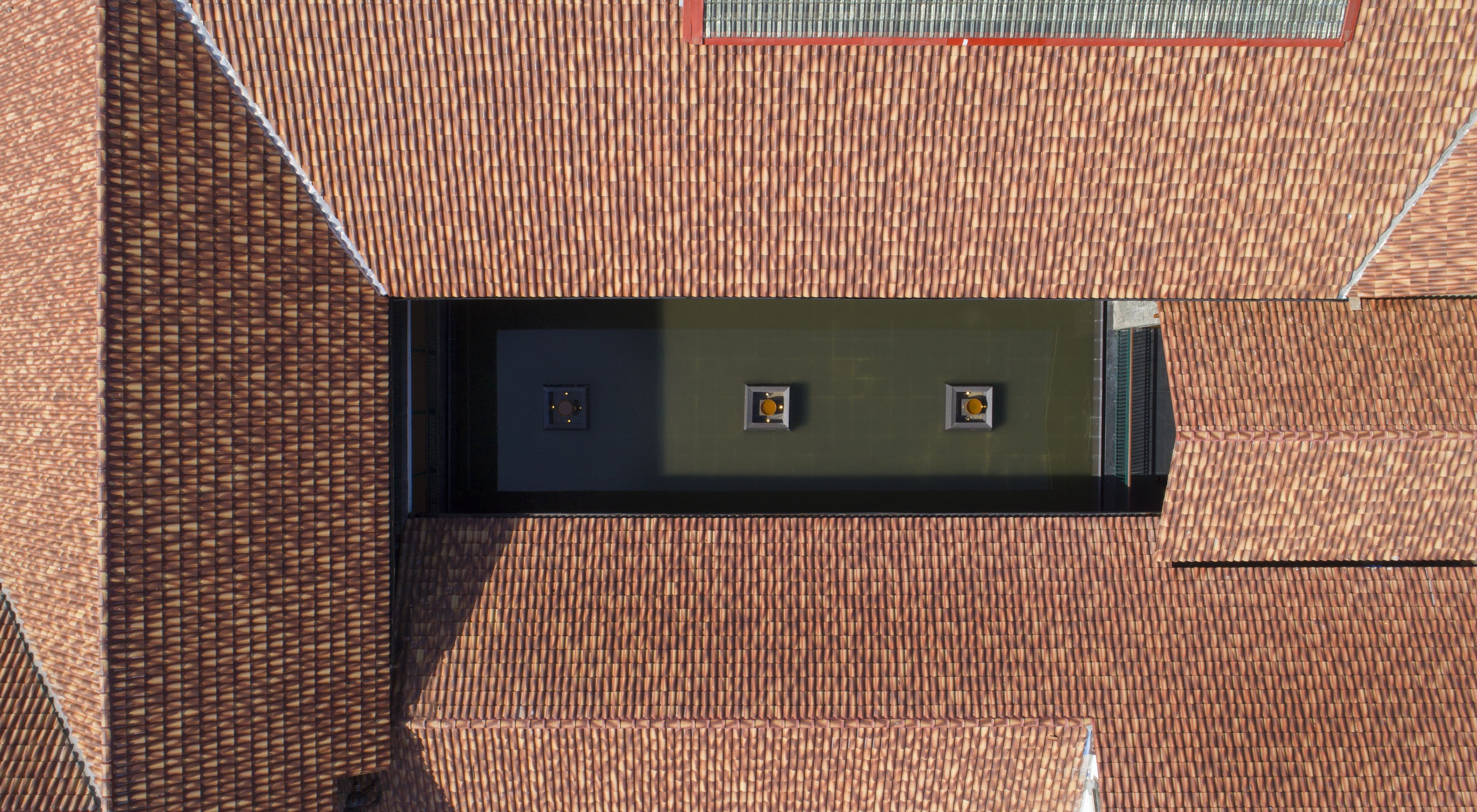 A building with a tiled roof and a rectangular window with two light fixtures.