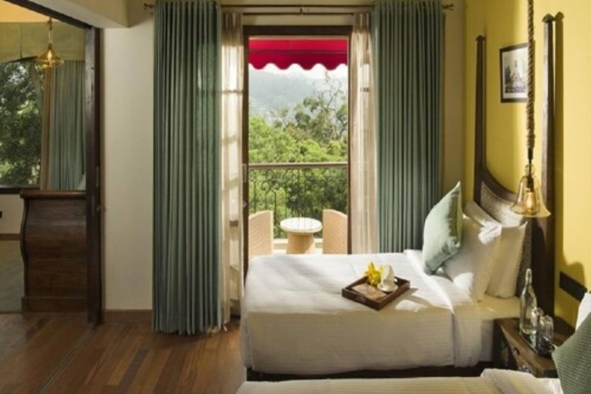 Une chambre à coucher comprenant un lit, une table de chevet, un miroir, une fenêtre avec des rideaux et une vue sur la verdure à l’extérieur.