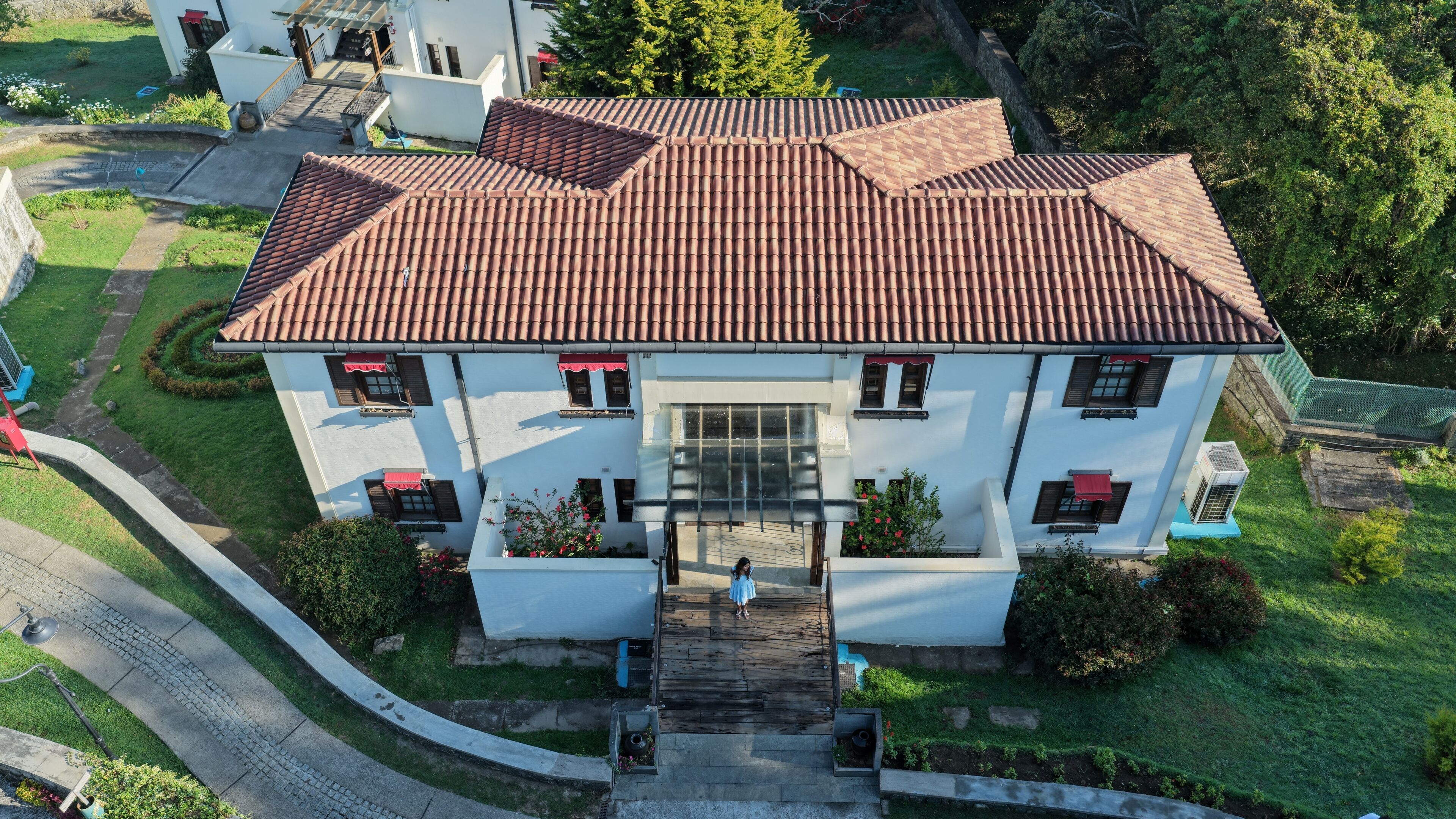 A two-story building with a tiled roof, a central entrance, and a small porch area.