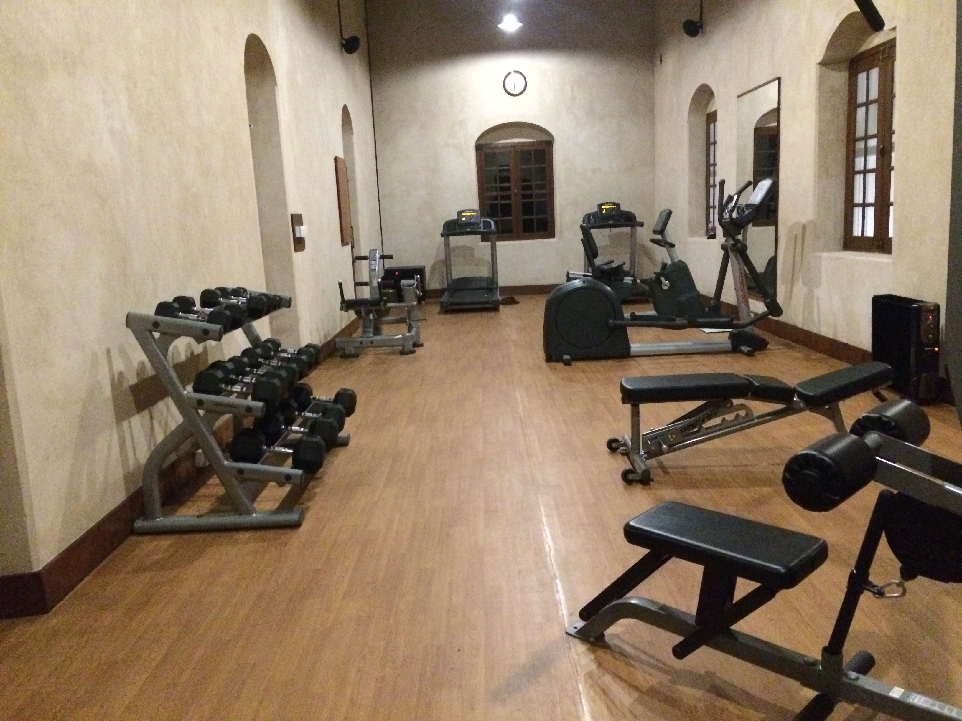 A gym with various exercise equipment, including dumbbells, benches, and cardio machines.