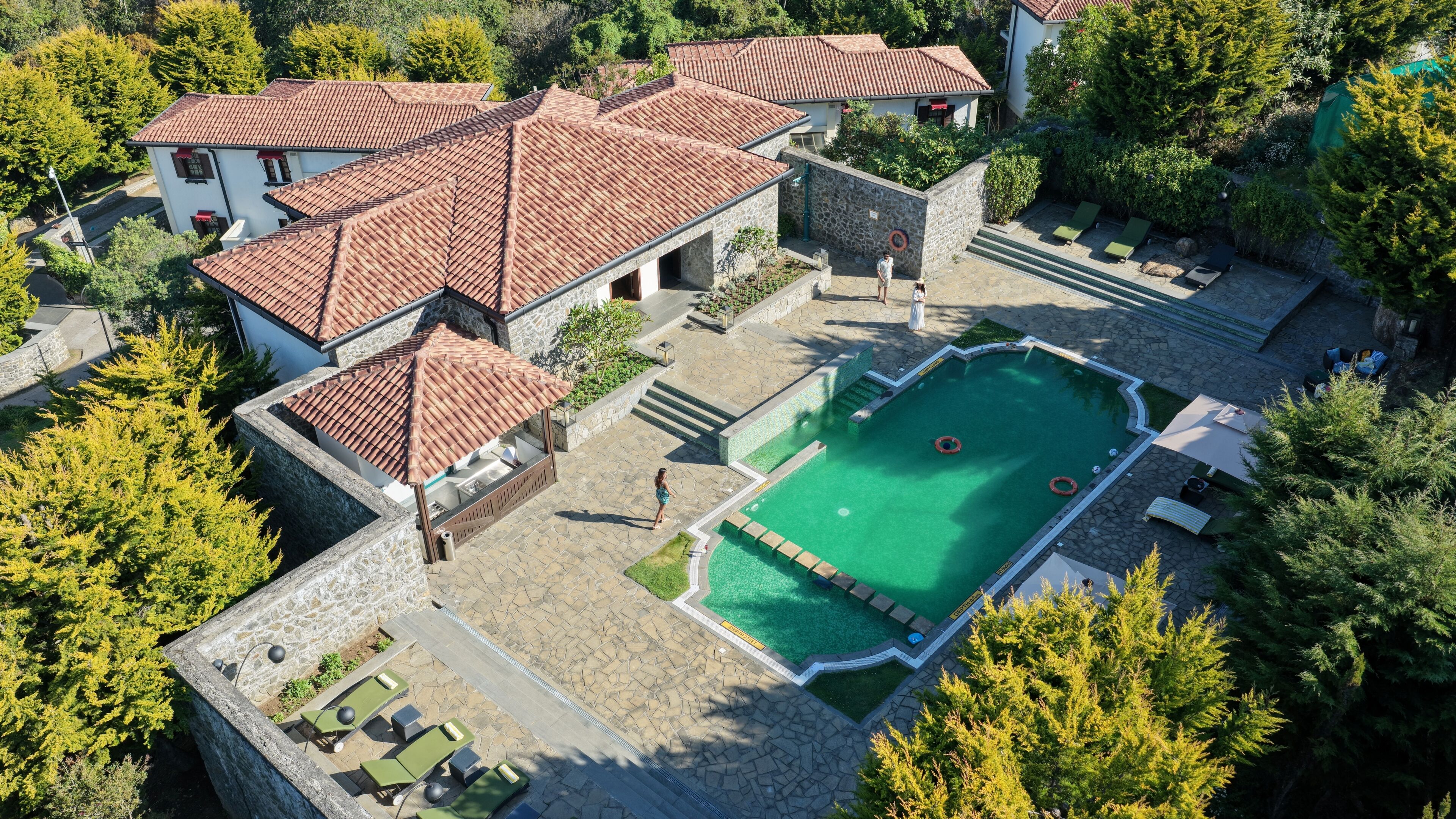 En boligejendom med swimmingpool, stenskær og en have.
