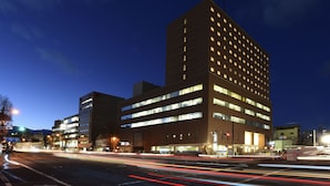 Un hotel de diversos pisos amb un disseny arquitectònic modern, destacant un edifici cantonada amb finestres il·luminades.