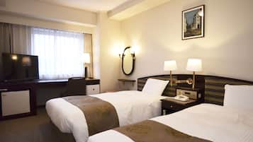 A hotel room with two beds, a desk with a television, a small refrigerator, and a painting on the wall.