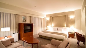Habitació d'hotel amb un llit gran, televisió, escriptori i una cadira.