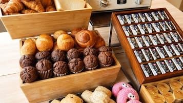 A variety of baked goods including pastries, muffins, and cookies in wooden boxes.