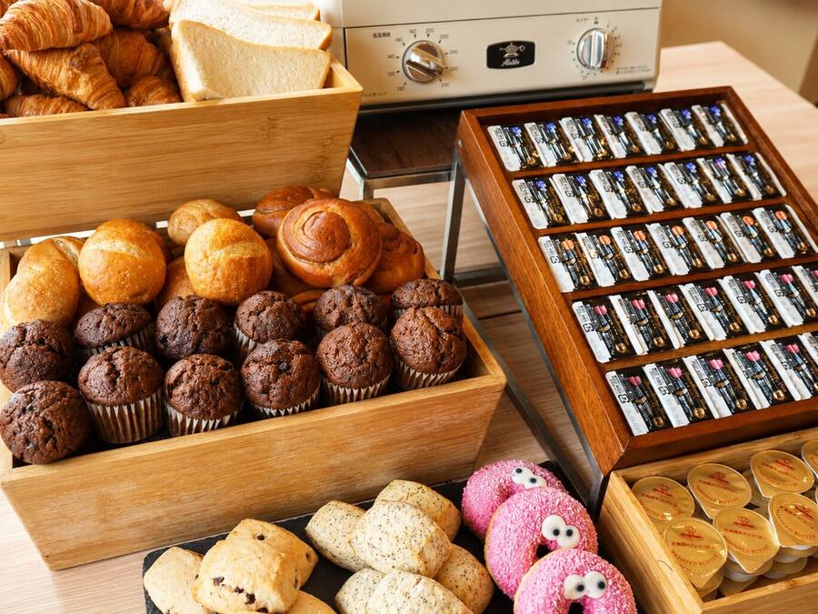 A variety of baked goods including pastries, muffins, and cookies in wooden boxes.