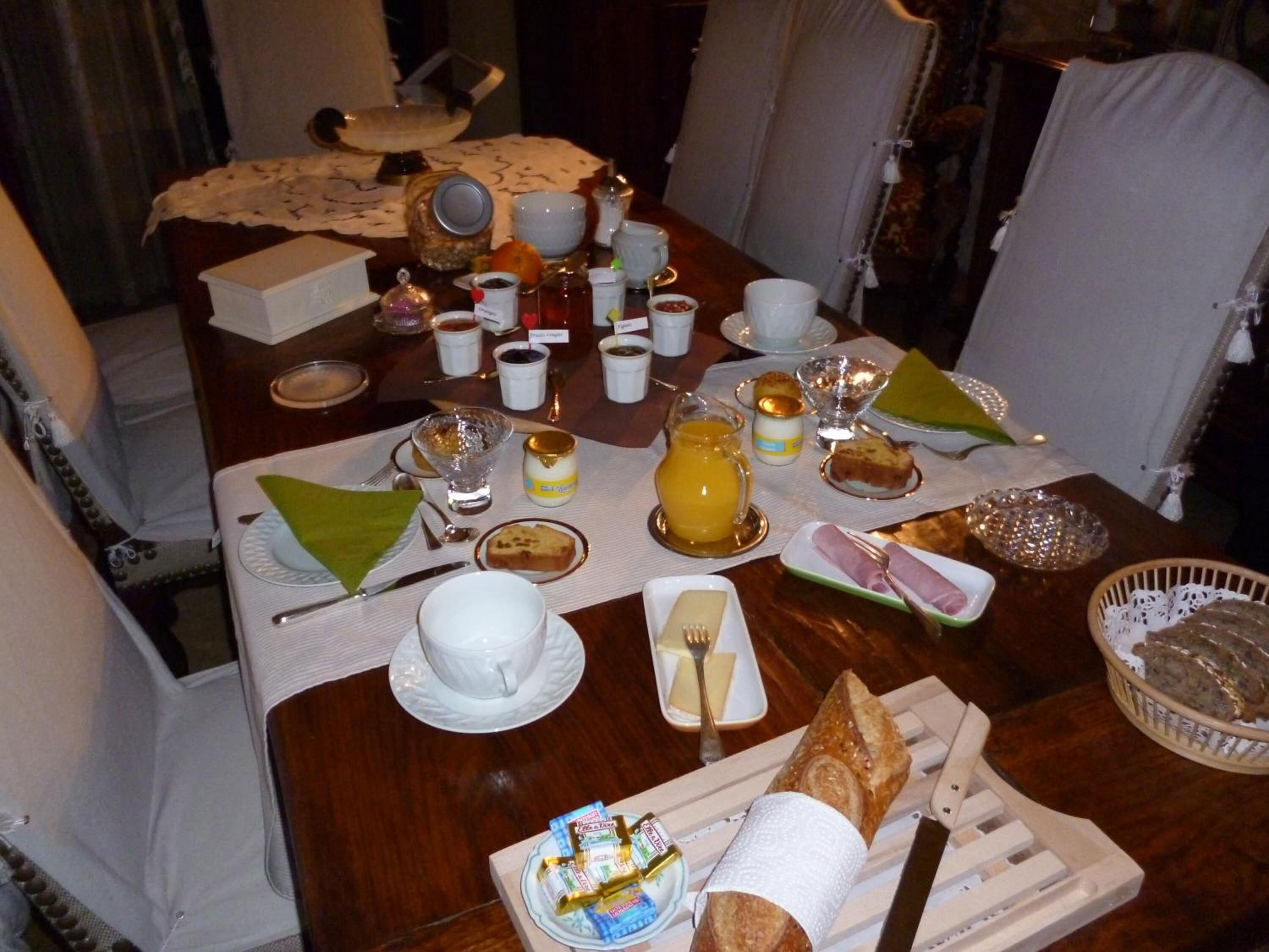 Une table de petit-déjeuner dressée avec divers plats, notamment des pâtisseries, des fruits et des boissons.