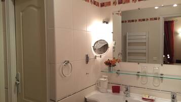 Un baño con lavamanos blanco, repisa de vidrio, espejo redondo y toallero.
