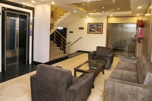 A lobby with a sofa, armchairs, a coffee table, an elevator, and a staircase.