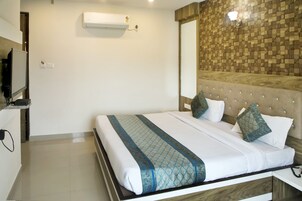 Una habitación de hotel con cama, televisión, aire acondicionado y pared con diseño de madera.