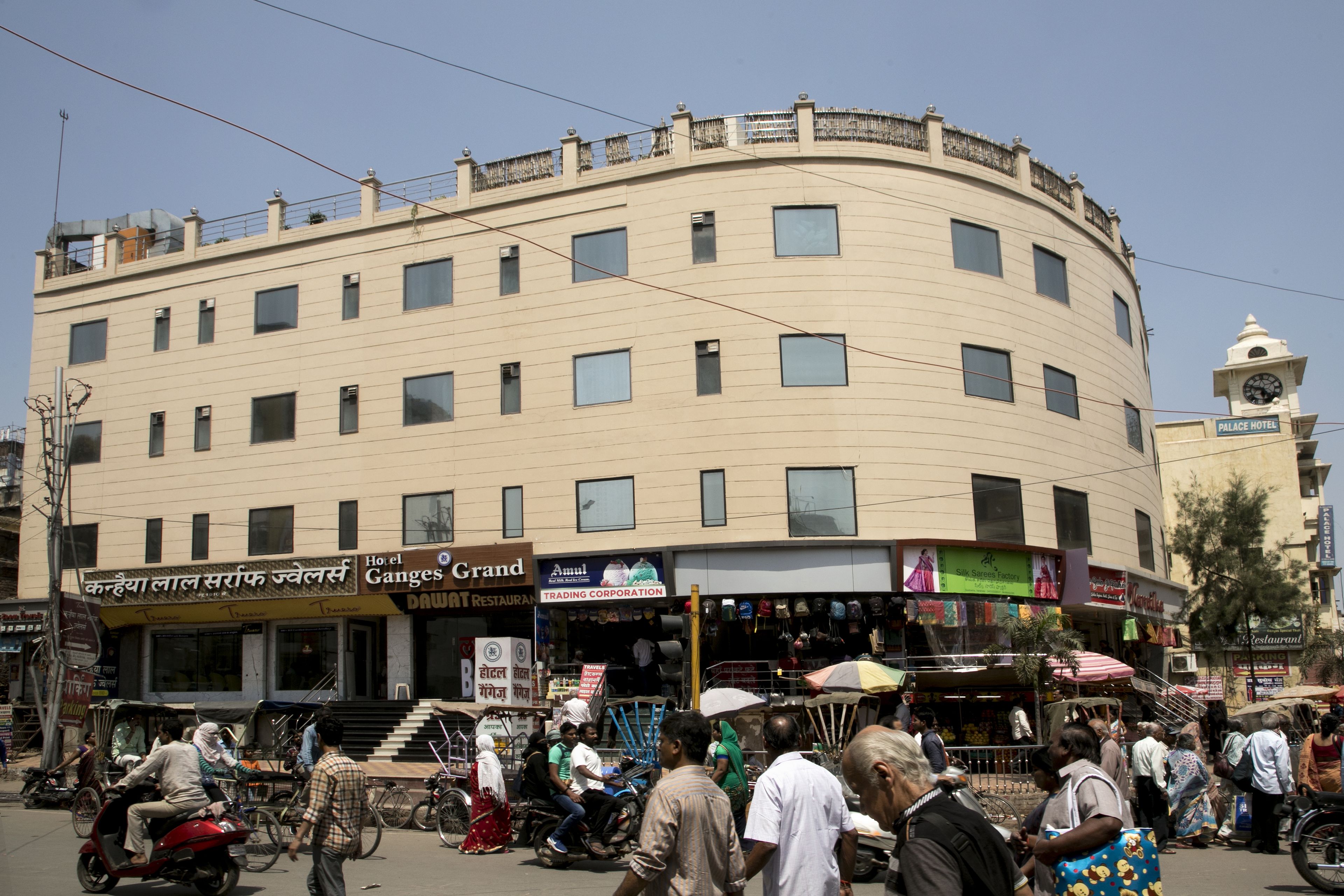 Ein mehrstöckiges Hotel mit geschwungener Fassade, mehreren Geschäften im Erdgeschoss und einem Uhrturm.
