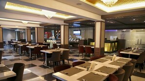 Un restaurante moderno con suelo de cuadros, varias mesas de comedor con sillas y una zona de bar.