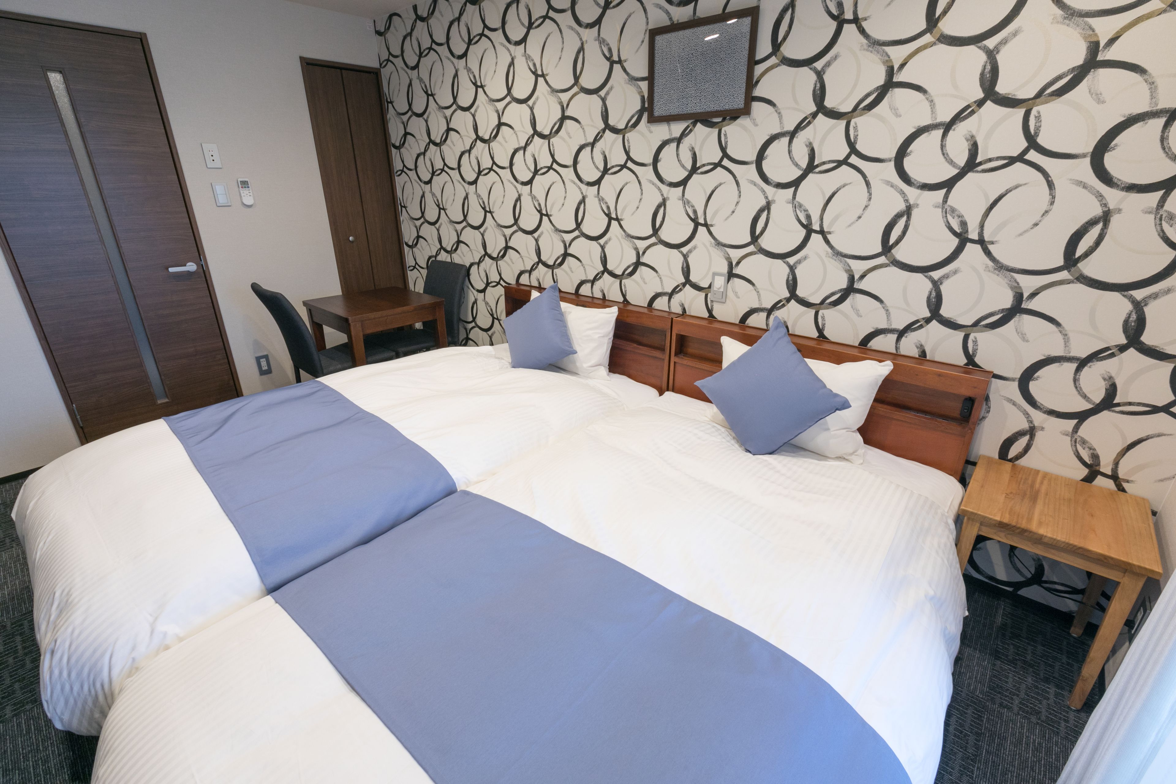 A hotel room with a large bed, two bedside tables, a desk, and a chair.