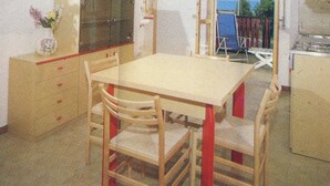 Quarto com uma mesa e cadeiras de madeira, um espelho e janela com vista para árvores.