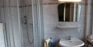 A bathroom with a glass-enclosed shower, a white sink, and a mirror above the sink.