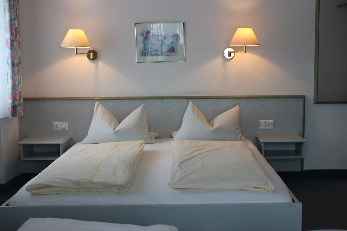 A neatly made bed with white linens and pillows, two bedside tables with lamps, and a framed picture on the wall.