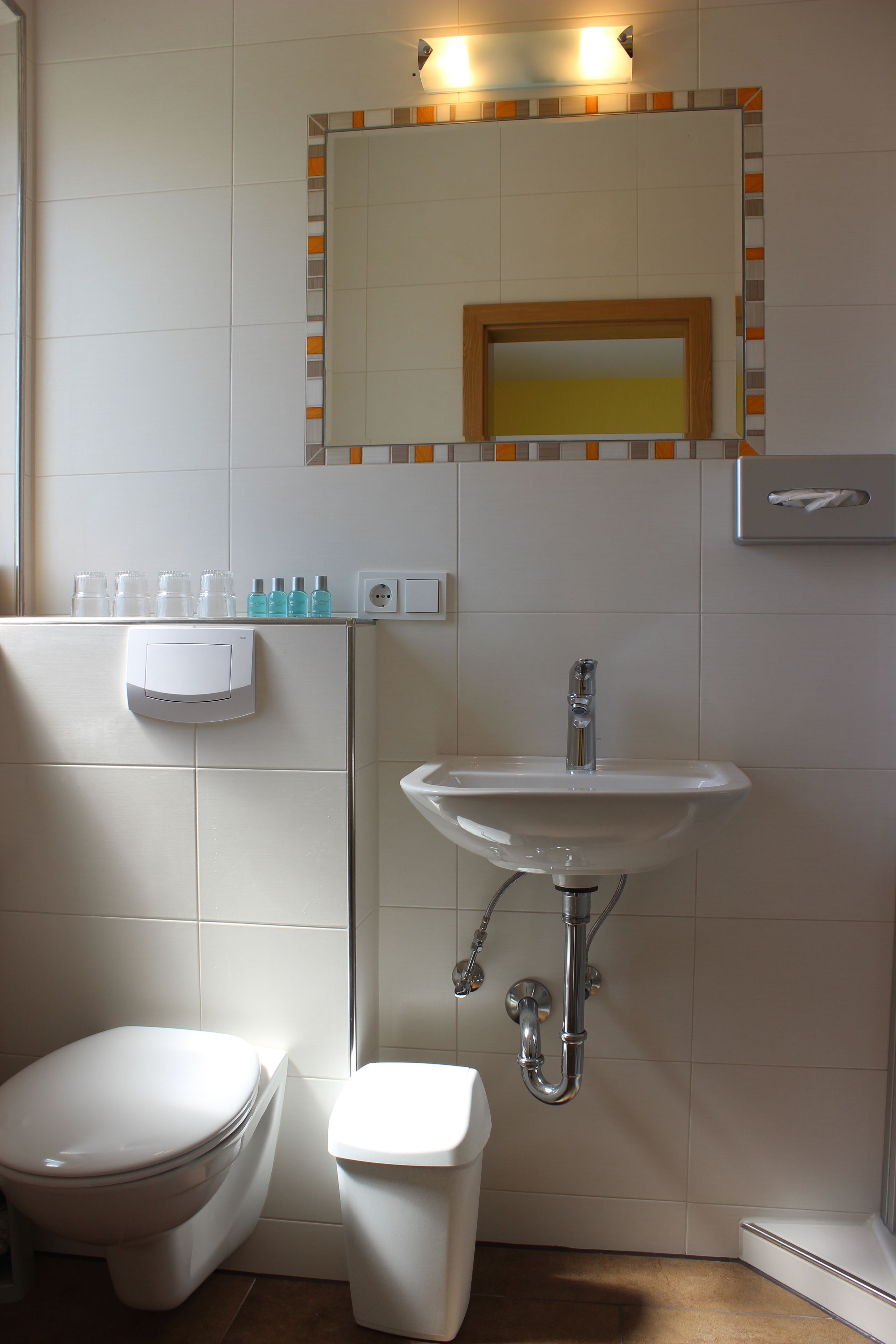 A bathroom with a toilet, sink, and mirror.