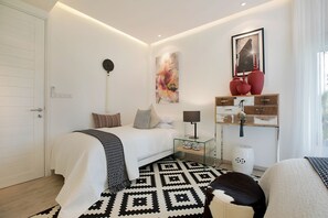 Een moderne slaapkamer met een bed, nachtkastje, lamp en decoratieve accessoires.