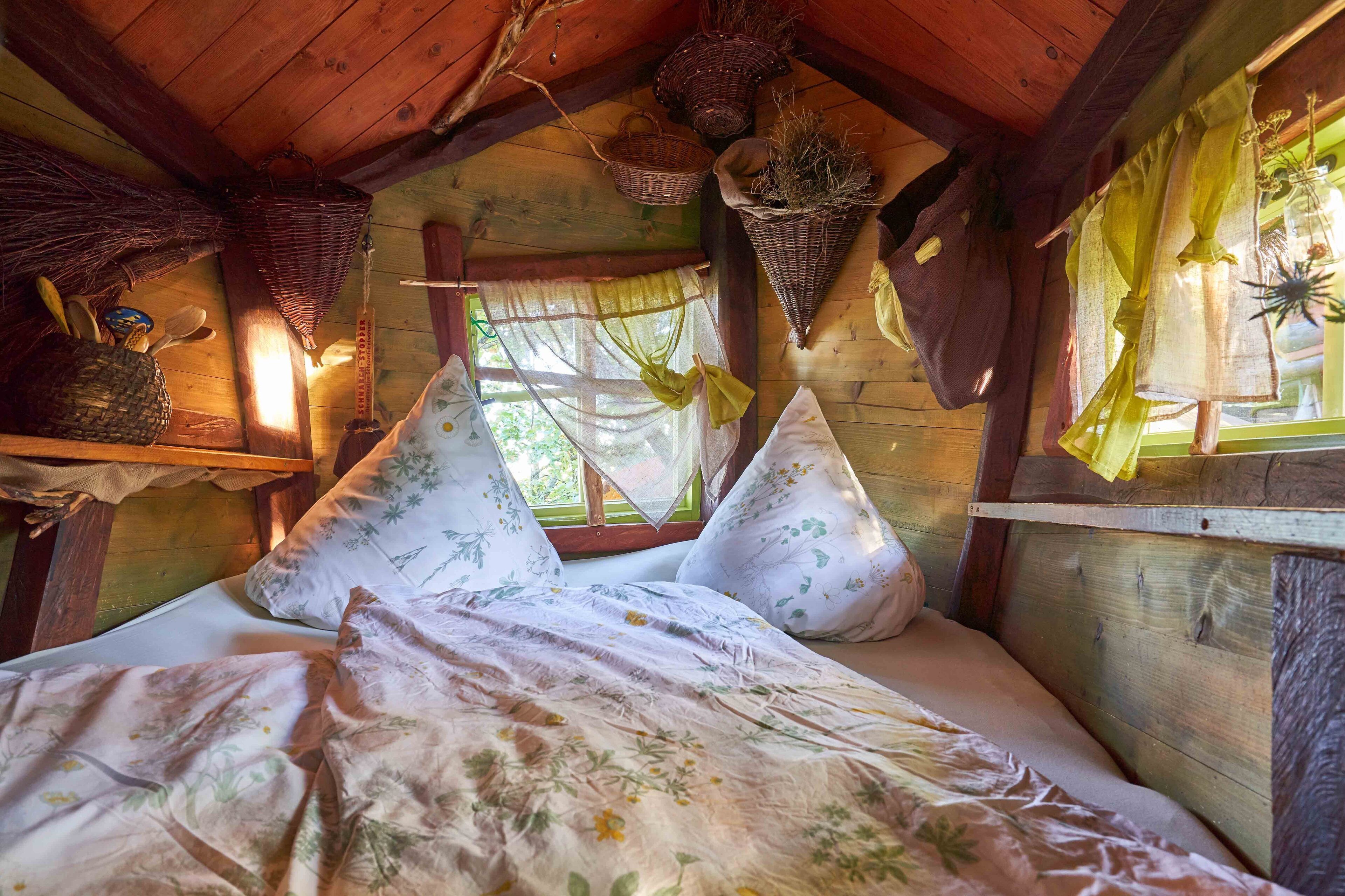 A cozy wooden cabin bedroom with a bed, pillows, and a window with a view.