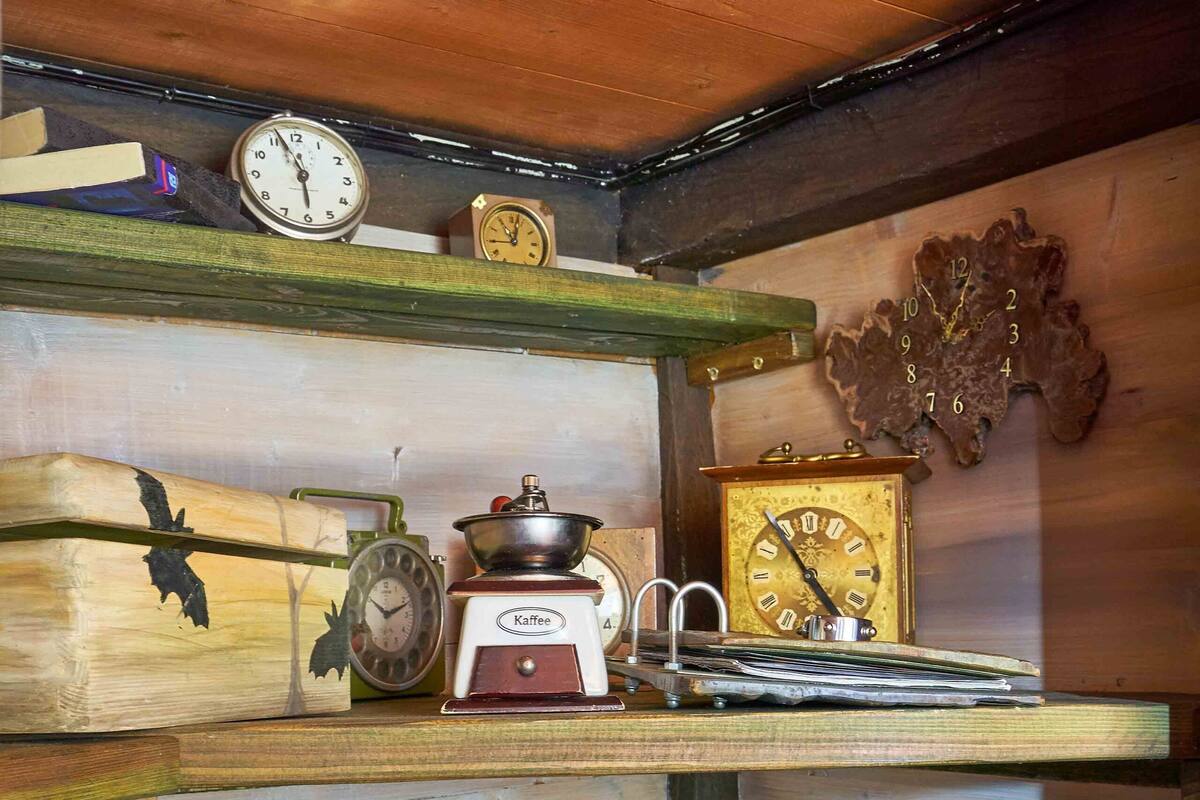 A rustic wooden shelf with a kettle, a coffee maker, and a clock.