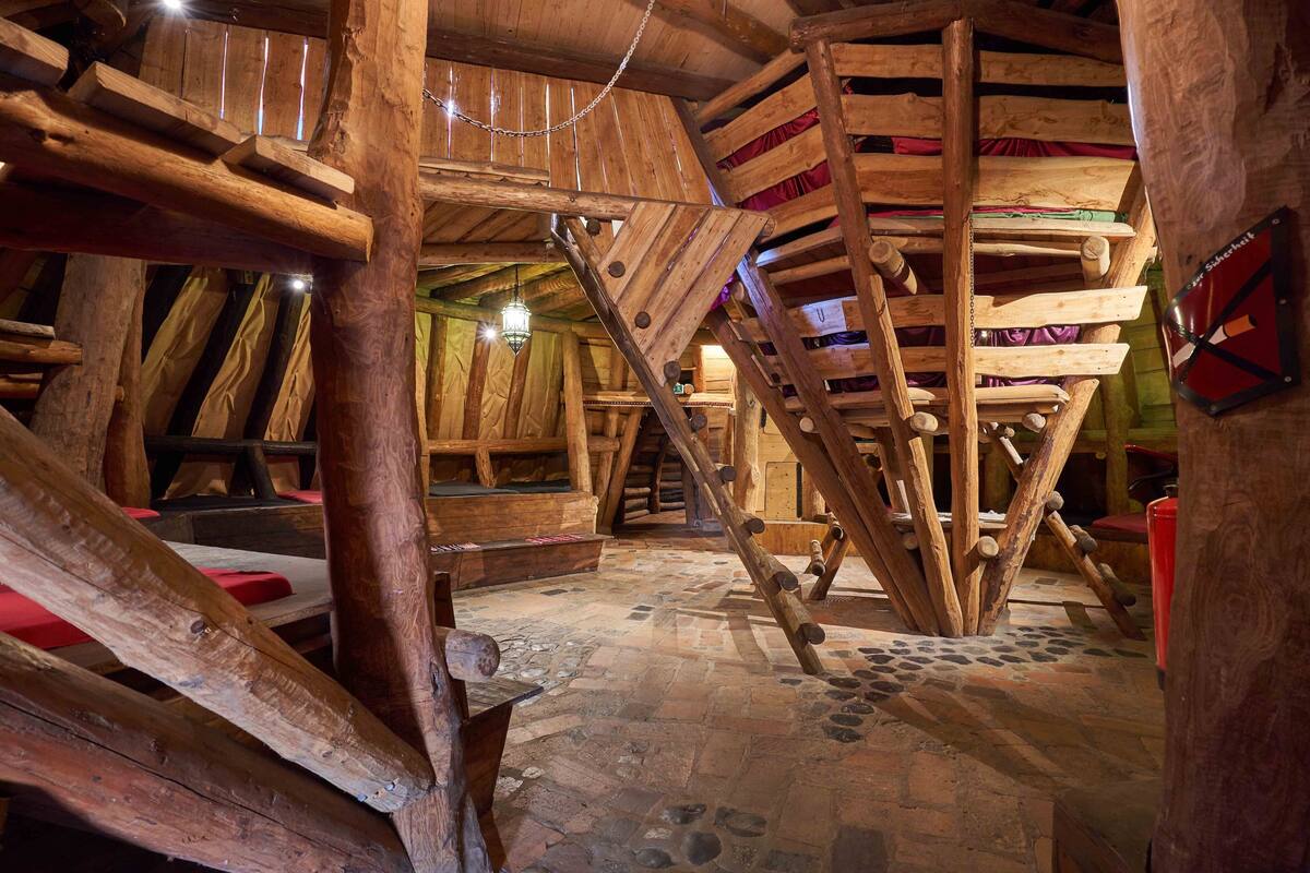 A rustic wooden interior with a spiral staircase, stone flooring, and a wooden ceiling.