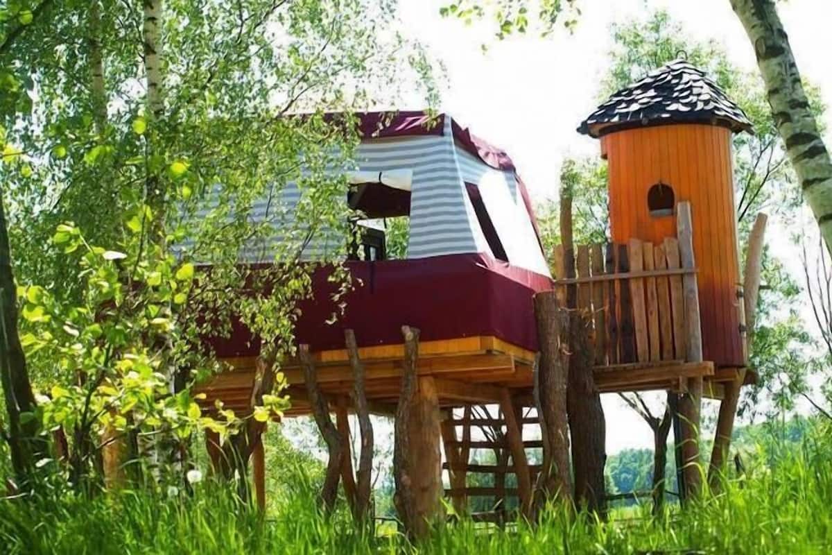 A treehouse with a striped exterior and a wooden deck.