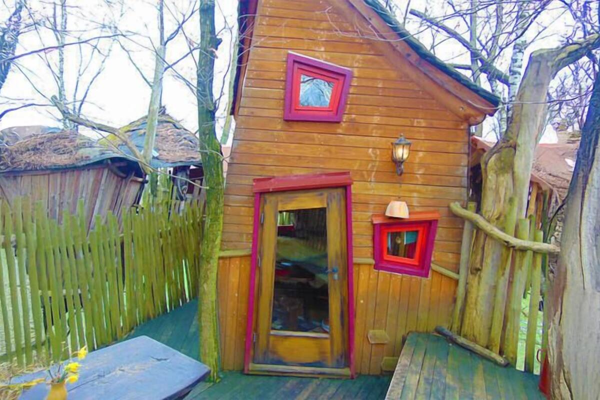 A wooden cabin with a door, a small window, and a light fixture.