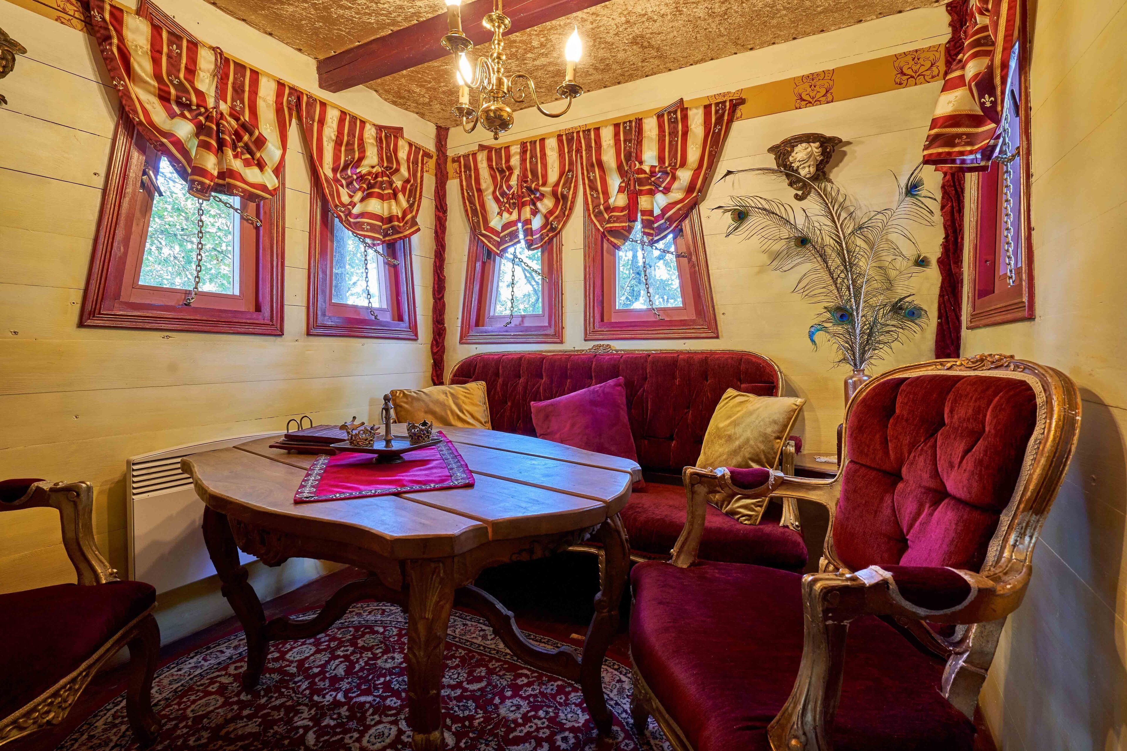 A room with a wooden table, red velvet sofa, and a chandelier.