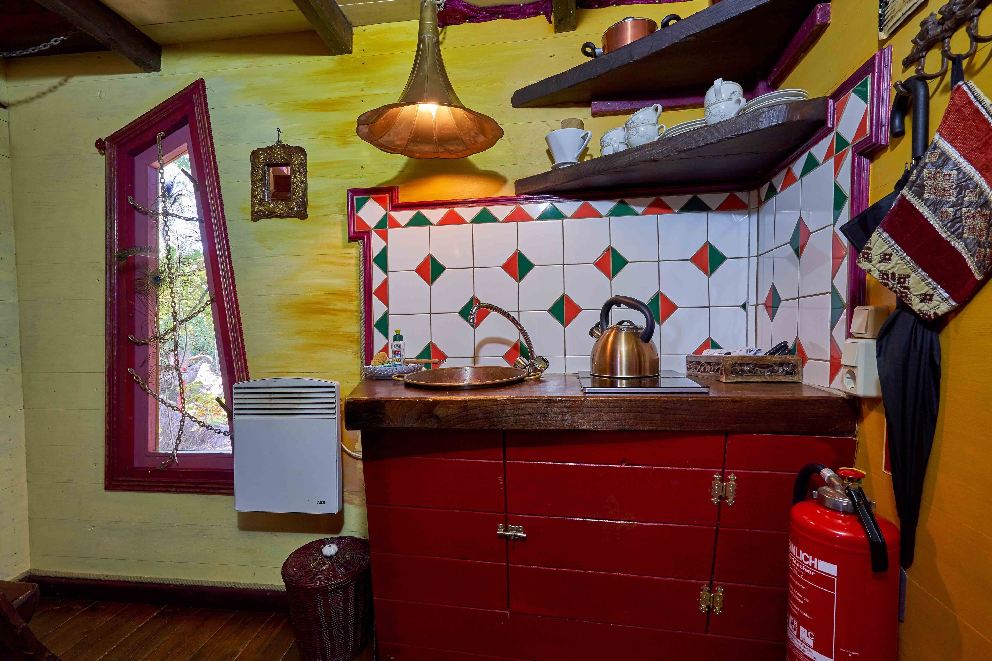 A kitchen with a red cabinet, a hanging light fixture, and a fire extinguisher.