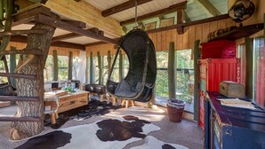 A rustic wooden interior with a hanging chair, wooden table, and a cowhide rug. - Die Geheime Welt von Turisede (Neisseaue)