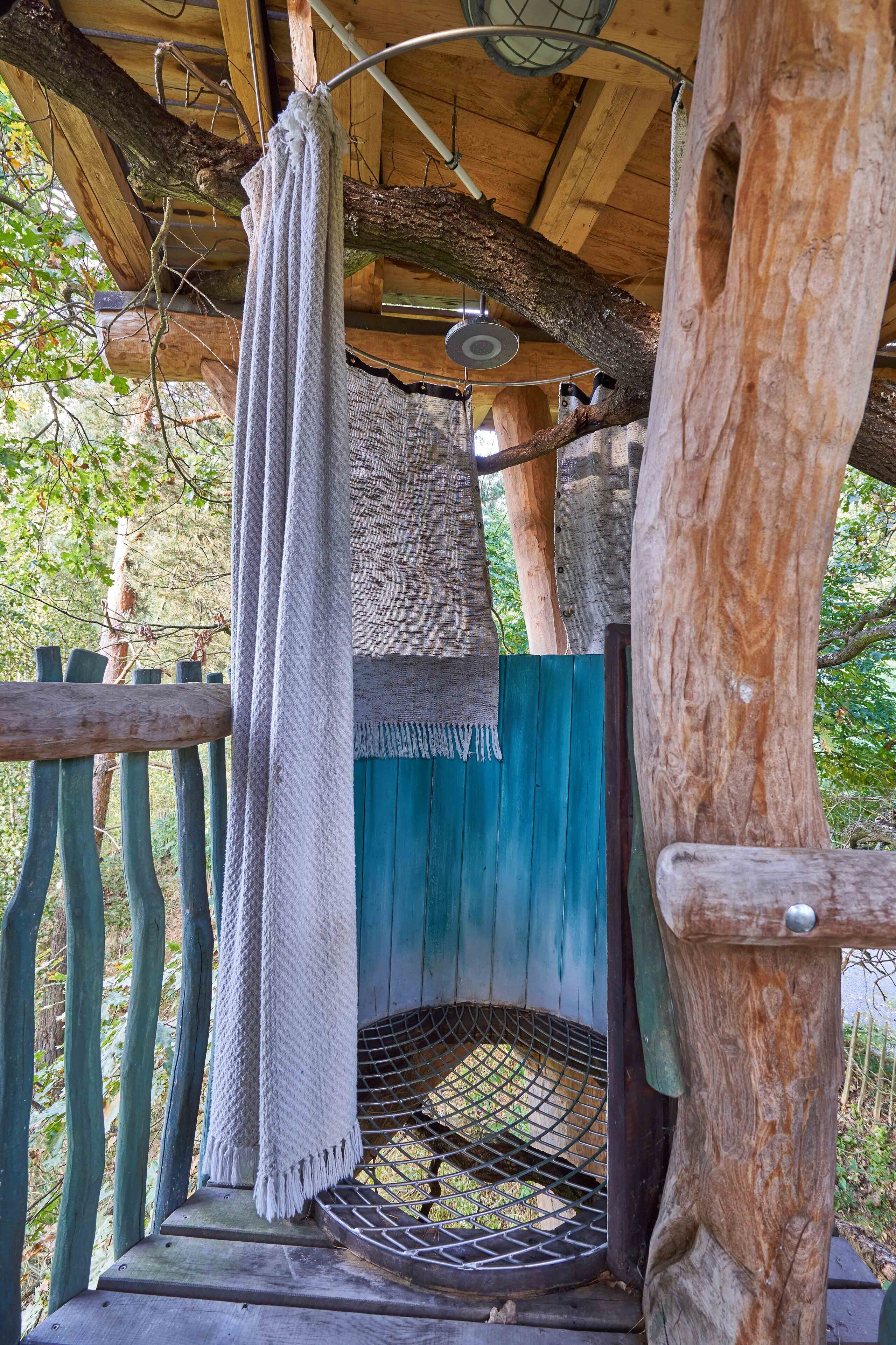 Una construcción rústica de madera con una toalla colgada, una puerta azul y una reja de metal.