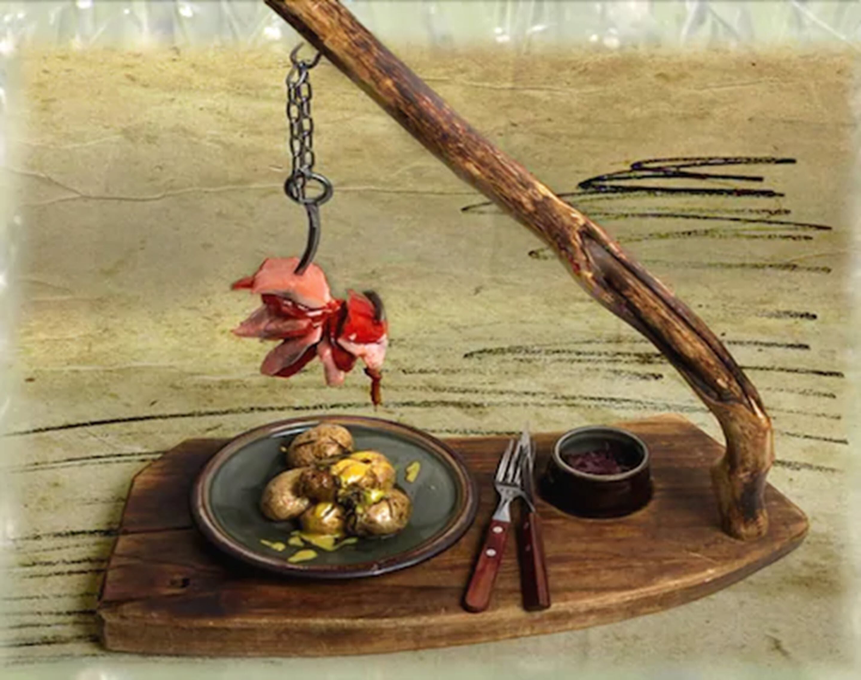 Een rustieke houten tafel met een bord eten, een kleine kom en een paar tangen.