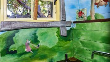 A room with a window, a sink, a red cloth, a painting of a woman, and a wall with a green landscape.